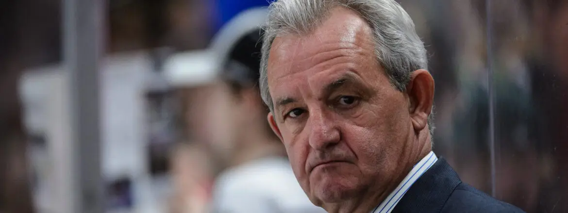 Close-up of a serious older man with gray hair and a thoughtful expression.