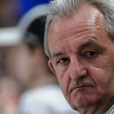Close-up of a serious older man with gray hair and a thoughtful expression.