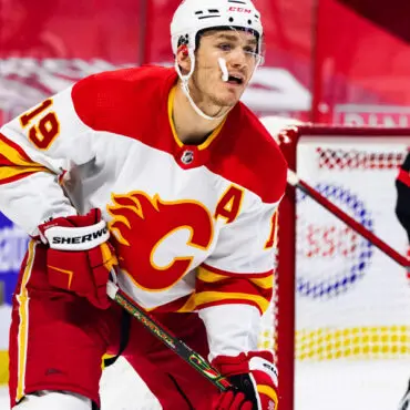 Hockey player in Calgary Flames uniform on ice during a game.