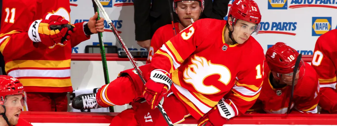 Two hockey players in red and orange jerseys competing for the puck.