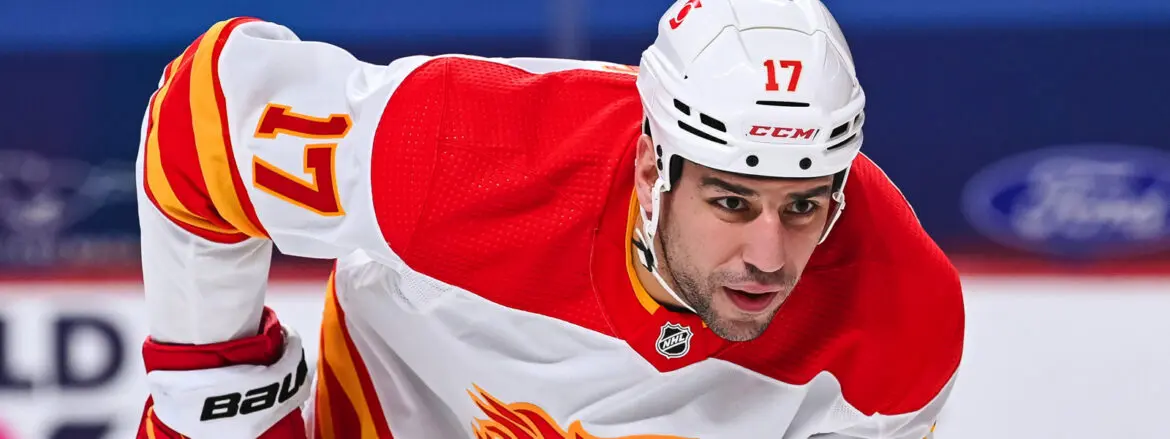 Hockey player in white and red uniform intensely focused on the game.