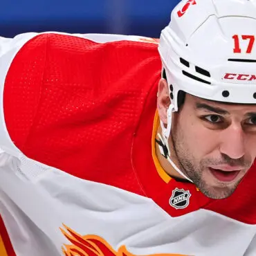 Hockey player in white and red uniform intensely focused on the game.