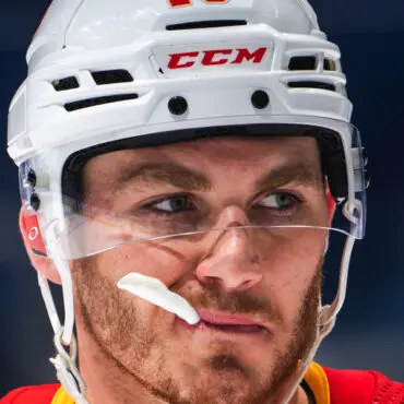 Close-up of a focused hockey player wearing a white CCM helmet.