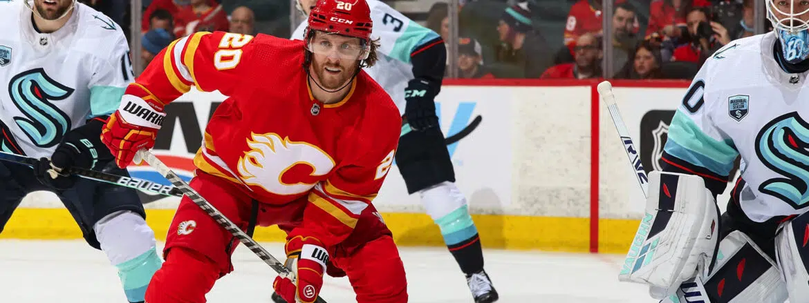 Hockey player in red Calgary Flames jersey skating on ice during a game.