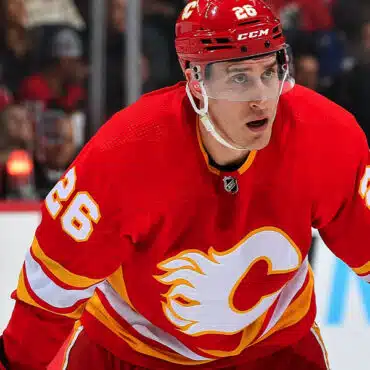 Hockey player in red Calgary Flames jersey focused during a game.