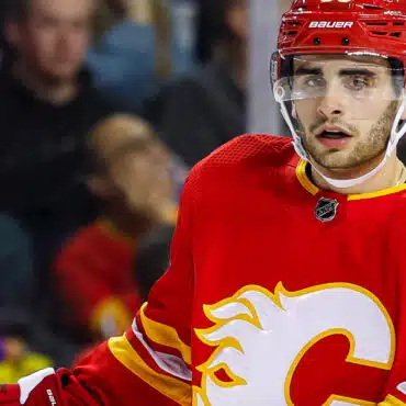 Hockey player in red Calgary Flames jersey on ice rink.