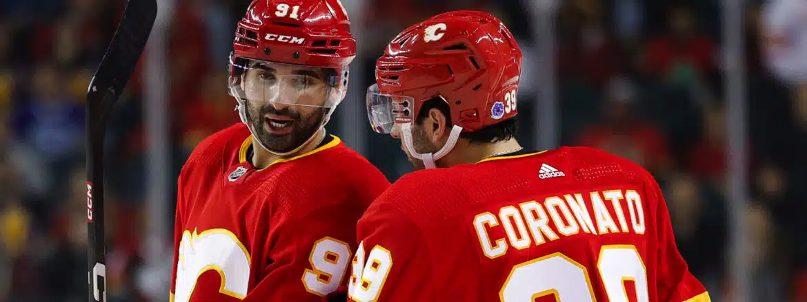 Two Calgary Flames hockey players in red jerseys during a game.
