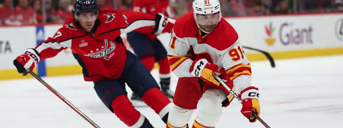 Two hockey players in action on the ice, one in red and white, the other in red and blue.