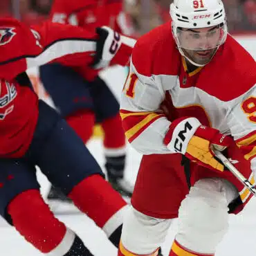 Two hockey players in action on the ice, one in red and white, the other in red and blue.
