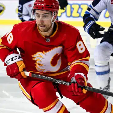 Hockey player in red Calgary Flames uniform skating on ice.