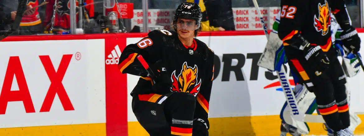Hockey player in black Calgary Flames jersey on the ice.