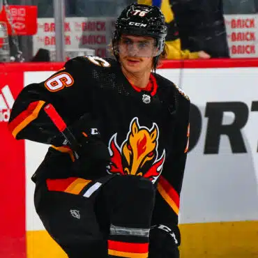 Hockey player in black Calgary Flames jersey on the ice.