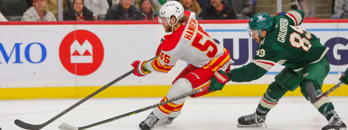 Ice hockey player in red and yellow uniform skating during a game.