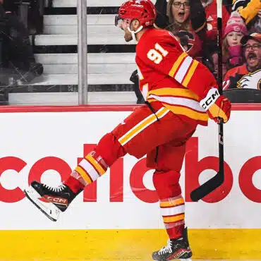 Hockey player in red uniform celebrates a goal on the ice rink.