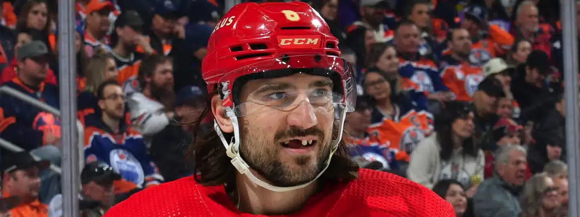 Hockey player with missing teeth and a red helmet during a game.