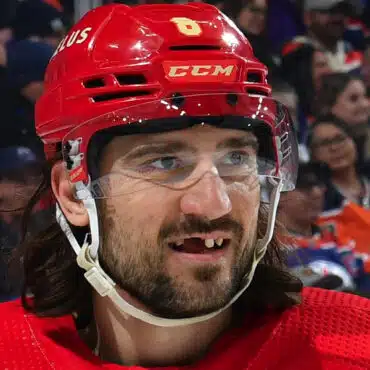 Hockey player with missing teeth and a red helmet during a game.