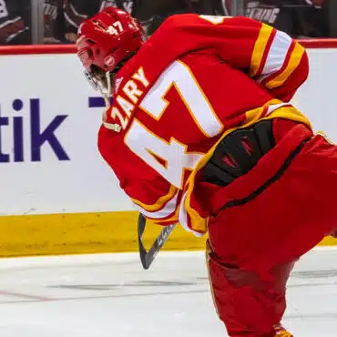 Hockey player in red jersey skating on ice rink during a game.