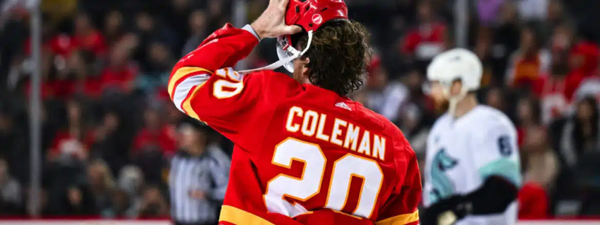 Hockey player Coleman in red jersey salutes crowd.