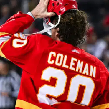 Hockey player Coleman in red jersey salutes crowd.