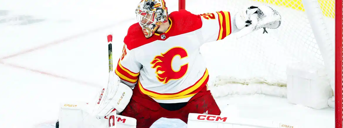 Hockey goalie in Calgary Flames uniform making a save.