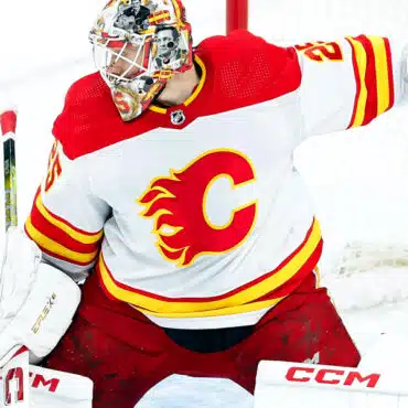 Hockey goalie in Calgary Flames uniform making a save.