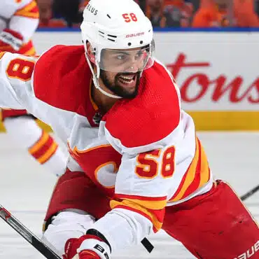 Ice hockey player in red and white uniform skating intensely.