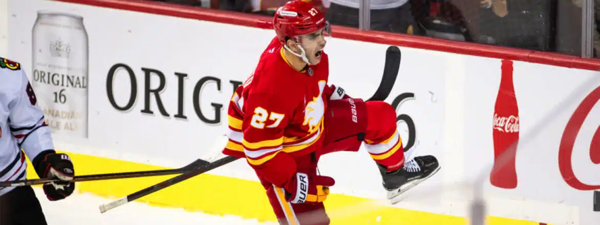 Ice hockey player celebrating a goal in red Calgary Flames uniform.