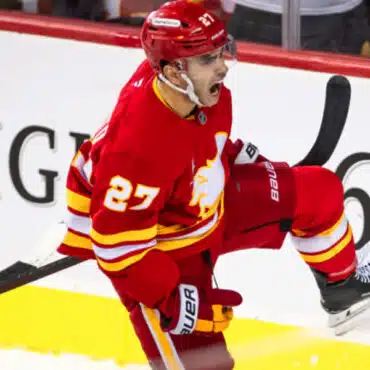 Ice hockey player celebrating a goal in red Calgary Flames uniform.