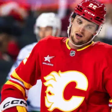 Hockey player in red Calgary Flames jersey on ice rink.