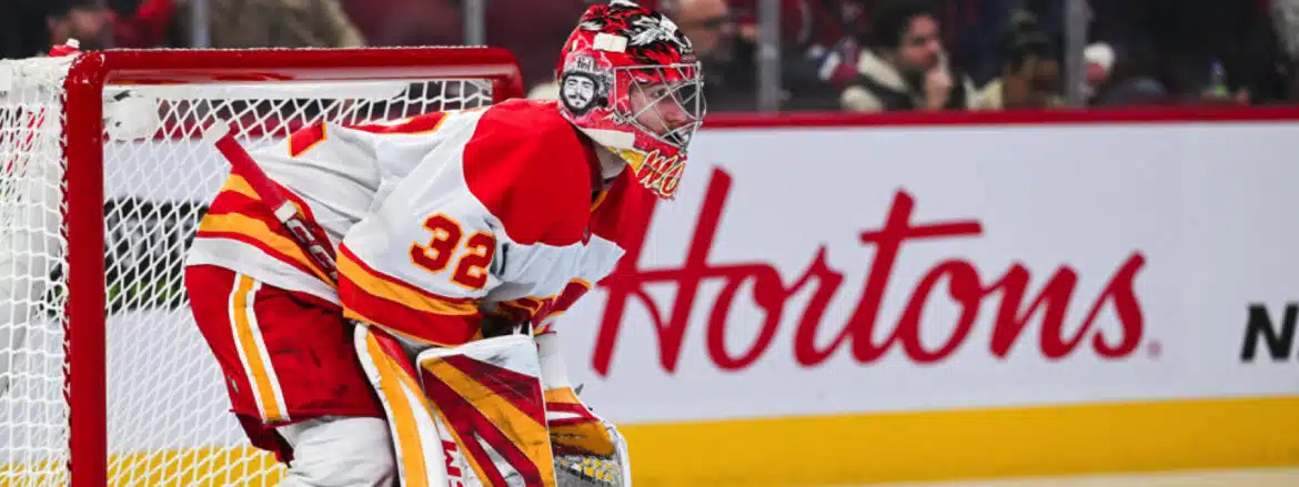 Hockey goalie in red and yellow gear focused during a game.