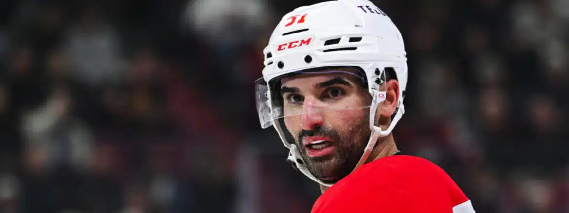 Close-up of a focused ice hockey player in a white helmet and red jersey.