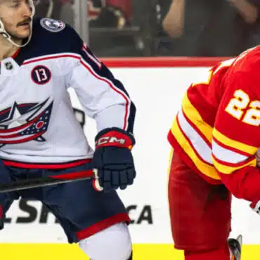 Two hockey players from opposing teams in action on the ice rink.