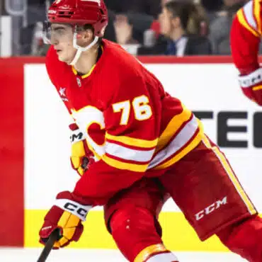 Hockey player in red and yellow uniform skating on ice during a game.