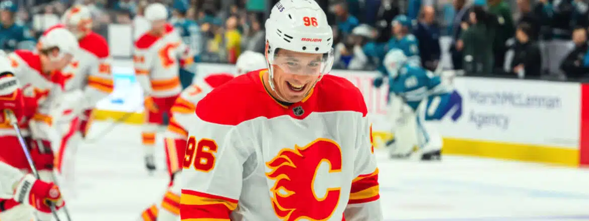Hockey player in Calgary Flames jersey smiling on ice.