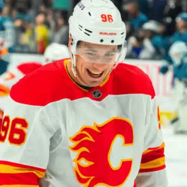 Hockey player in Calgary Flames jersey smiling on ice.