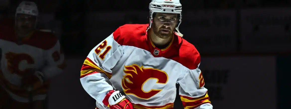 Hockey player in Calgary Flames jersey on ice rink.