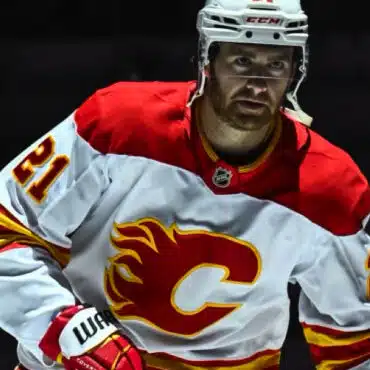Hockey player in Calgary Flames jersey on ice rink.