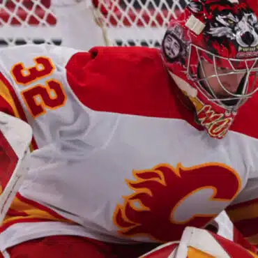 Hockey goalie in Calgary Flames uniform ready to defend the net.