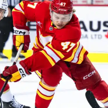 Ice hockey player in red jersey skating fast on the rink.
