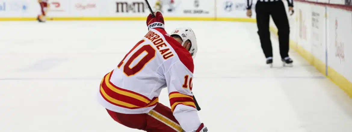Hockey player in white and red jersey celebrating on ice.
