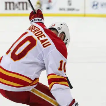 Hockey player in white and red jersey celebrating on ice.