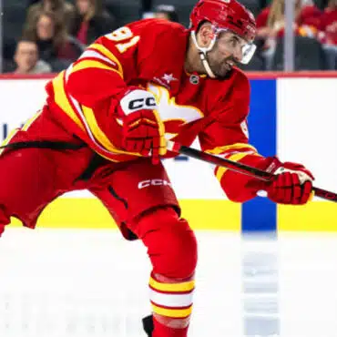 Hockey player in red uniform skating on ice during a game.