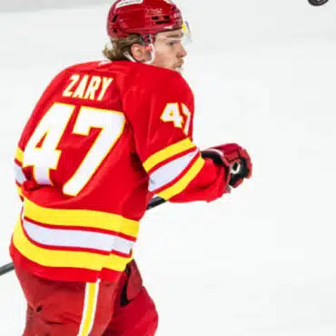 Ice hockey player in red jersey with number 47 skating on ice.