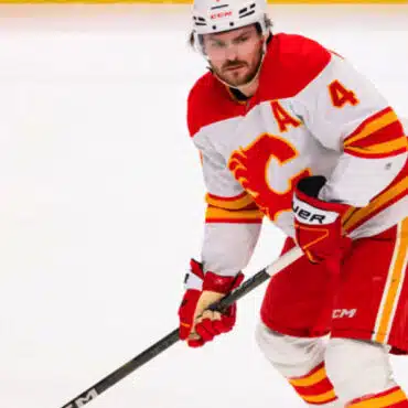 Hockey player in red and white Calgary Flames uniform on ice.