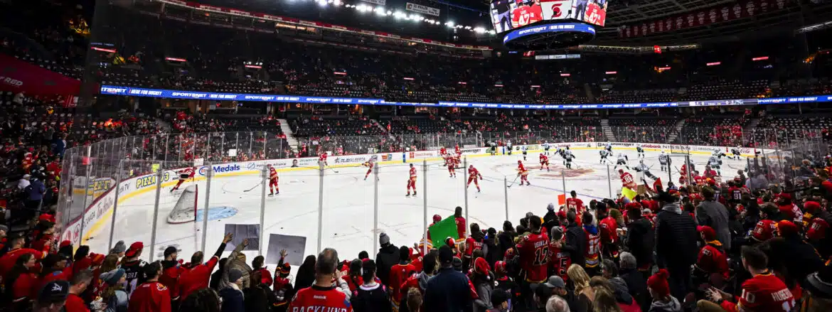 Crowded arena with players warming up on the ice rink before a hockey game.