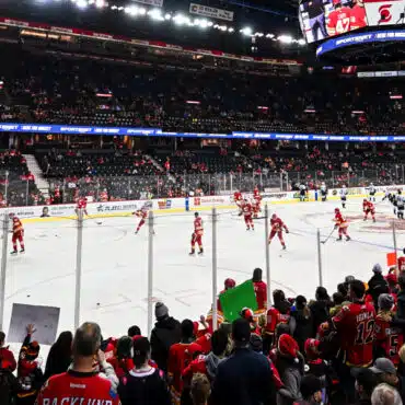 Crowded arena with players warming up on the ice rink before a hockey game.