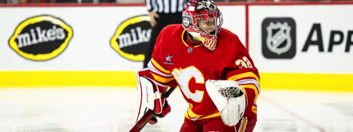 Ice hockey goalie in red Calgary Flames uniform ready to defend the goal.