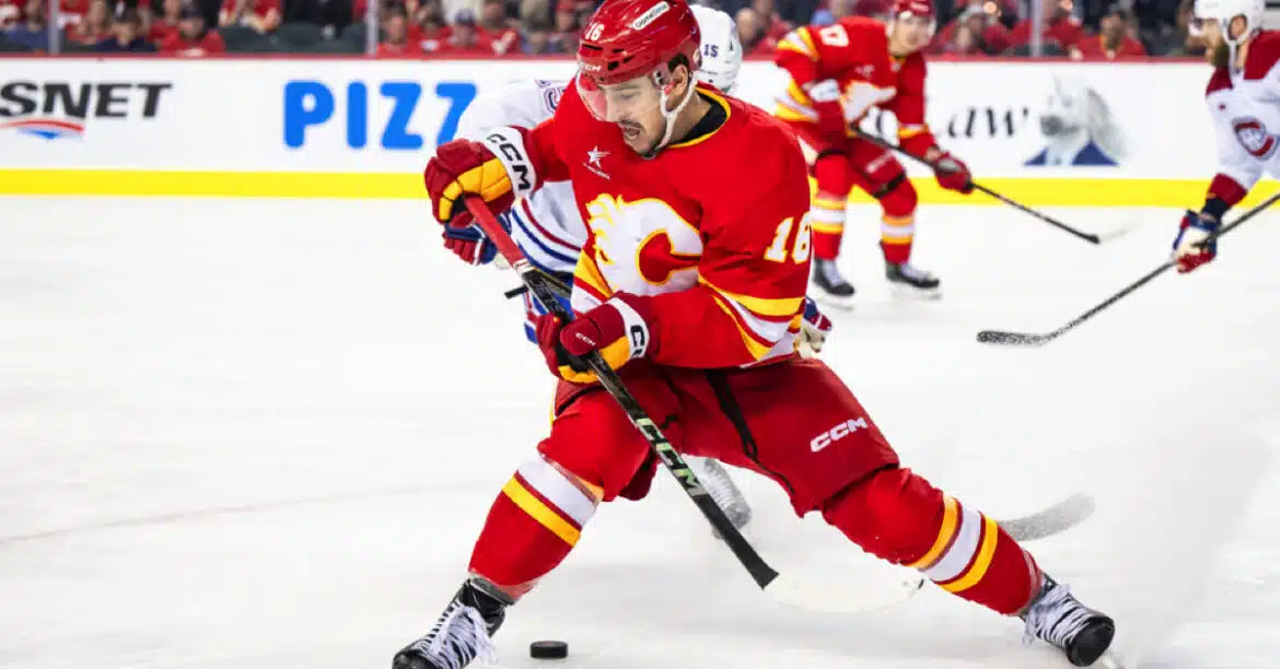 A Calgary Flames hockey player in red jersey skating with the puck.