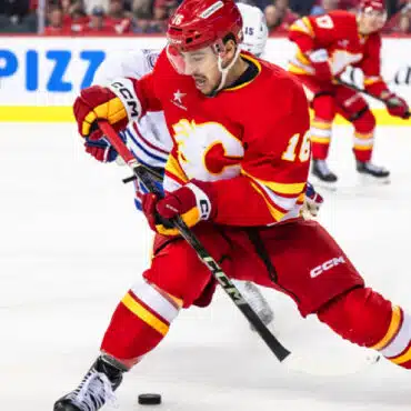 A Calgary Flames hockey player in red jersey skating with the puck.