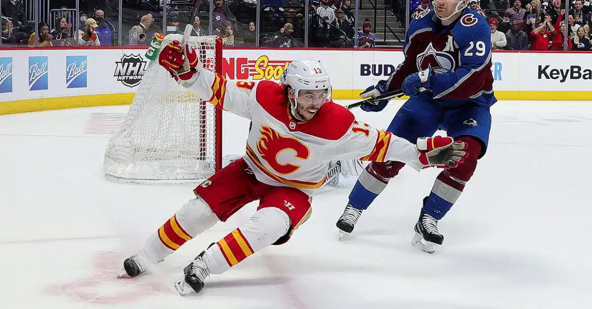 Ice hockey player in white and red uniform skating fast on the rink.